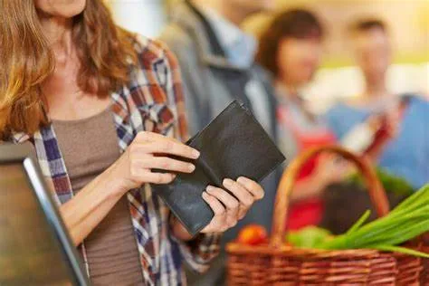 Woman checking an empty wallet while grocery shopping, highlighting the challenge of food affordability in Canada